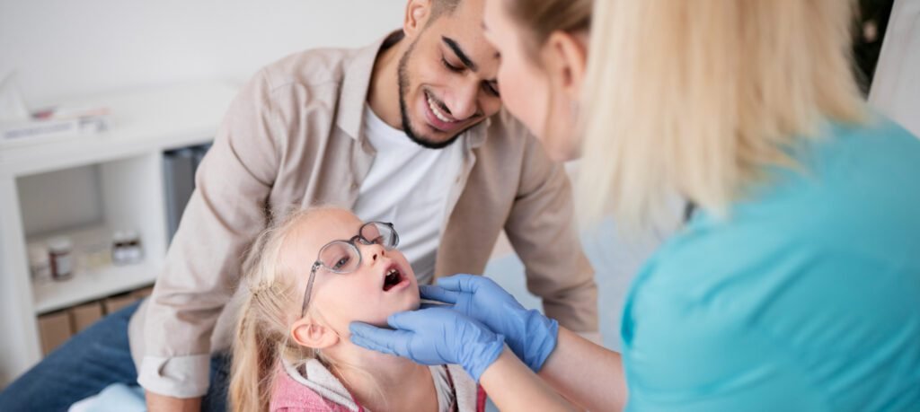Dentist examining infant using knee-to-knee technique with parent.