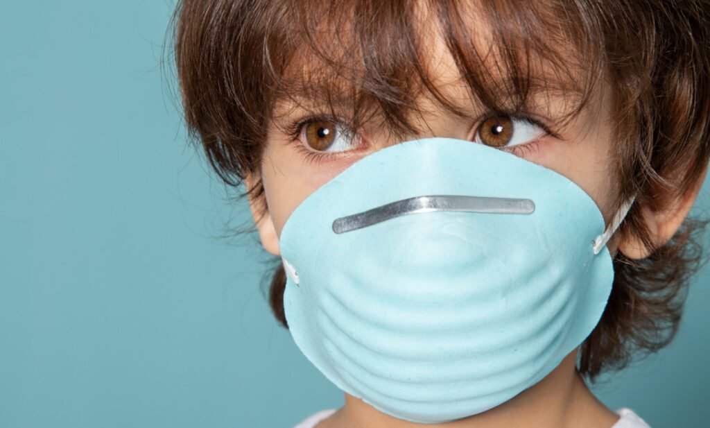 Child wearing facemask headgear with elastic bands.